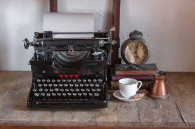 Natürmort ev iç ayrıntıları. Vintage retro gazeteci masaüstü fincan kahve, bakır sürahi, çalar saat, kitap, gazete, rustik tarzı ahşap arka plan üzerinde typewrittert.
