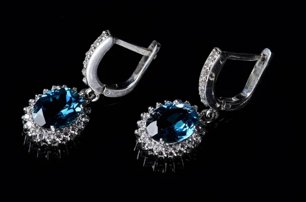Orecchini in argento con topazio blu isolato su fondo nero . — Foto Stock