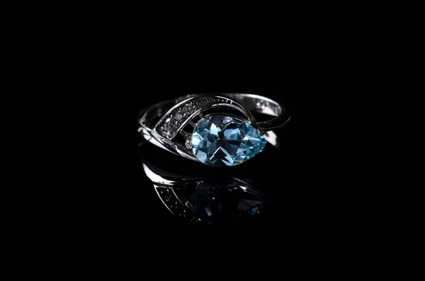 Srebrny pierścionek z niebieskim topaz na białym na czarnym tle. — Zdjęcie stockowe