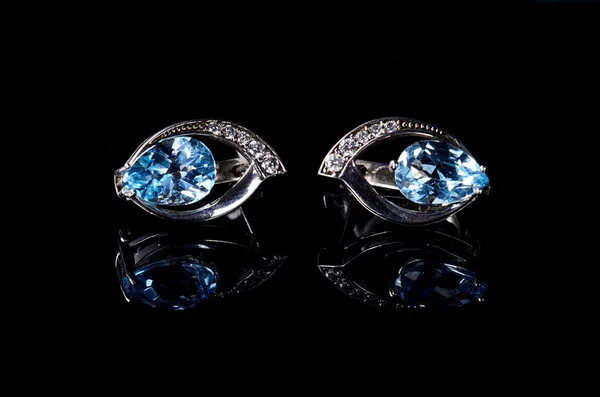 Orecchini in argento con gemma blu isolata su fondo nero . — Foto Stock