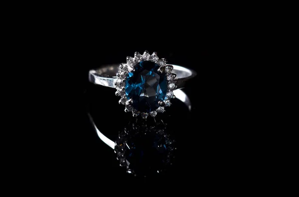 Silver ring with blue topaz isolated on a black background. — Stock Photo, Image