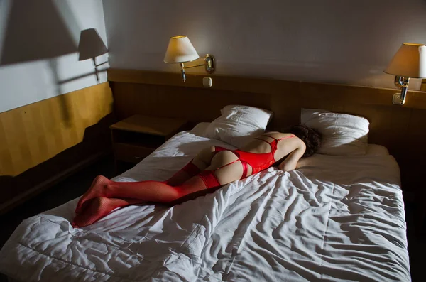 Sexy junge Frau in roter Unterwäsche auf dem Bett. — Stockfoto
