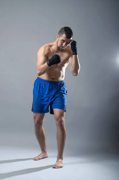 Portrait of kickboxer on a gray background. — Stock Photo, Image