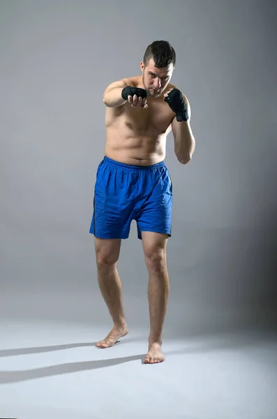 Portrait of kickboxer on a gray background. — Stock Photo, Image