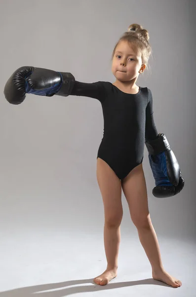 Niña en medias negras y guantes para el boxeo en una espalda gris — Foto de Stock