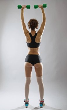 Elinde, dikiz dumbbells ile atletik genç kadın.