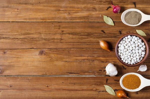 Wooden spoons with spices on a wooden table, space for text.