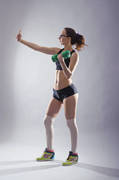 Атлетичная женщина с гантели в руке делает селфи на sm — стоковое фото