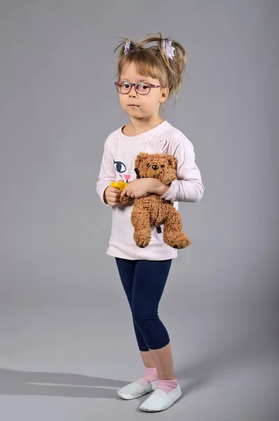 Beautiful girl with a teddy bear on a gray background. — Stock Photo, Image