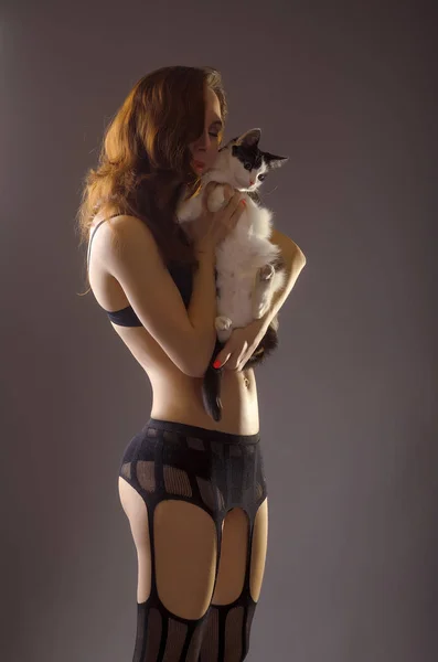 Sexy vrouw met pluizige kat in haar armen. — Stockfoto