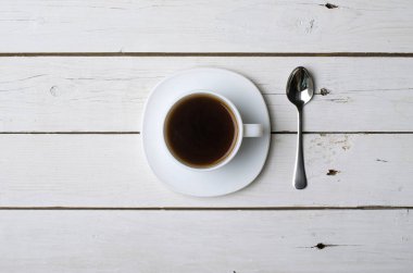 Bir fincan sıcak kahve masada bir beyaz tahta, üstten görünüm.