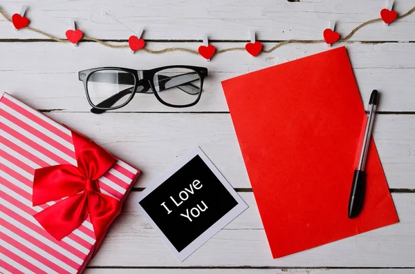 Een rode stukje papier en cadeau doos op een witte houten achtergrond. — Stockfoto