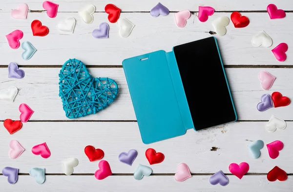 Smartphone and blue heart on a white wooden table. — Stock Photo, Image