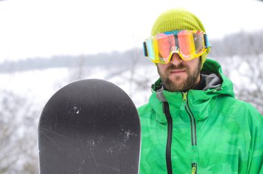 Genç adam ayakta bir snowboard kar ve bir protectiv
