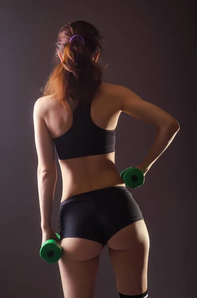 Спорт молодая женщина делает упражнения с гантелями, вид сзади . — стоковое фото
