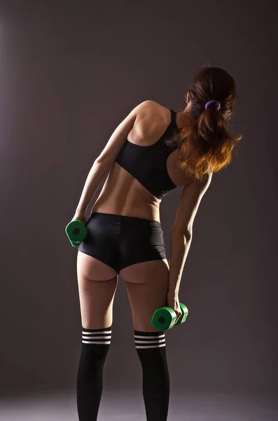 Sportovní mladá žena s činkami, pohled zezadu. — Stock fotografie