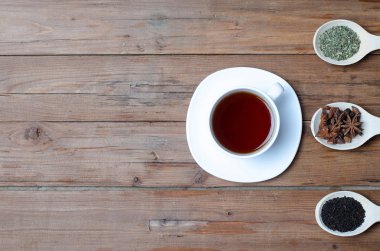 Bir fincan sıcak çay ve baharat ahşap bir masa üzerinde.