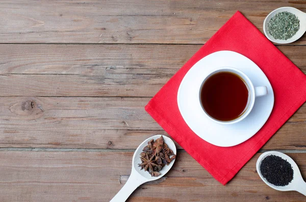 Kubek gorącej herbaty i przypraw na drewnianym stole. — Zdjęcie stockowe