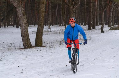 Aşırı dağ bisikleti karla kaplı ormanda.