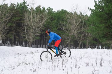 Aşırı dağ bisikleti karla kaplı ormanda.