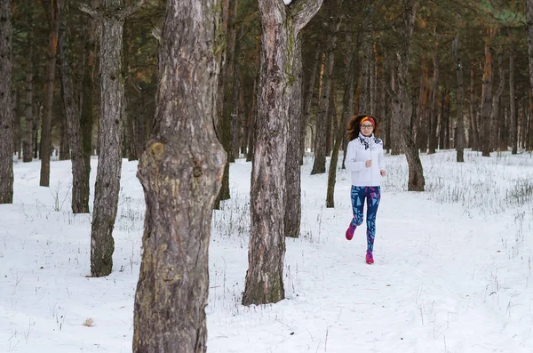 Deporte mujer joven corriendo en el bosque de invierno . — Foto de Stock