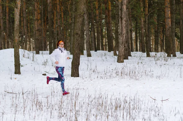 Deporte mujer joven corriendo en el bosque de invierno . — Foto de Stock