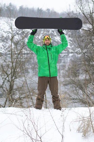 Сноубордист в яркой одежде позирует со сноубордом — стоковое фото