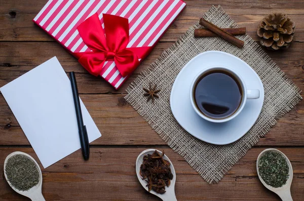 Una taza de café caliente, un regalo y una hoja de papel vacía en un coro — Foto de Stock