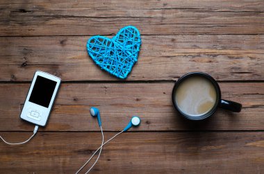 Bir fincan sıcak kahve ve ahşap bir sekme kulaklıktan olan bir oyuncu