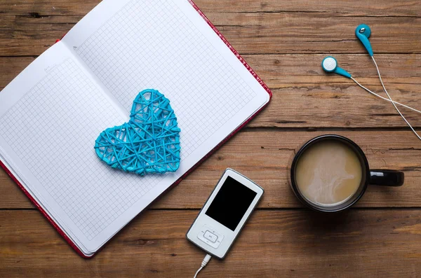 Une tasse de café, un cahier et un lecteur avec écouteurs sur un wo — Photo