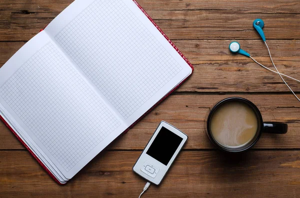 Une tasse de café, un cahier et un lecteur avec écouteurs sur un wo — Photo