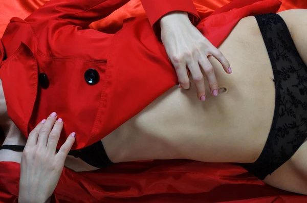 Sexy jovem mulher em uma capa de chuva vermelha e roupa interior . — Fotografia de Stock