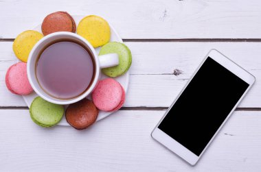 Bir fincan sıcak çay, renkli Badem Çerezler ve Smartphone'da bir 