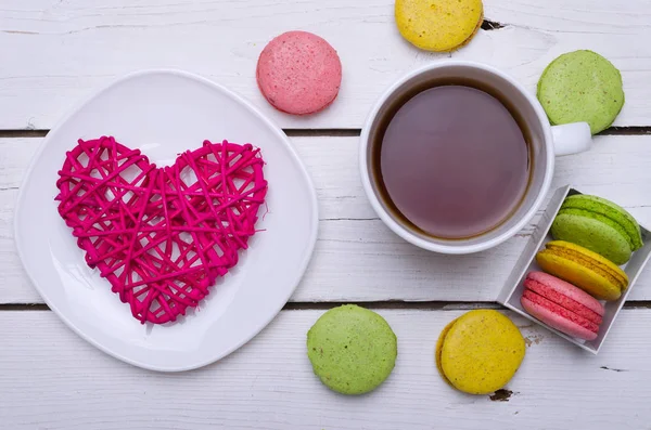 A cup of hot tea and krasochnochnoe macaroons on a wooden table. — Stock Photo, Image