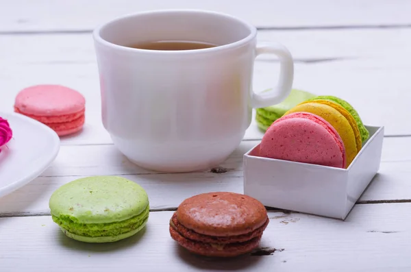 Galletas de almendras y una taza de té sobre una mesa blanca de madera . — Foto de Stock