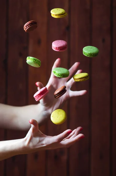 Macarrones moscas multicolores sobre las manos en una mesa de madera, enfoque — Foto de Stock