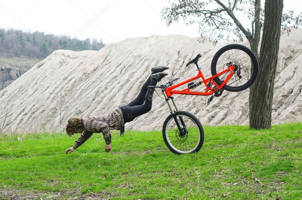 A young male extreme falls from a bicycle.