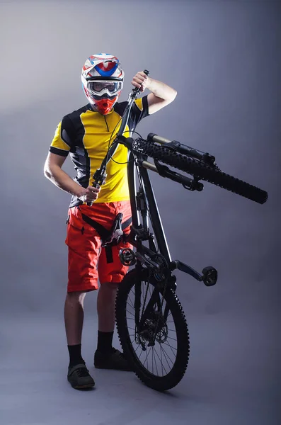 Portrait of a professional cyclist wearing a helmet on a gray ba — Stock Photo, Image