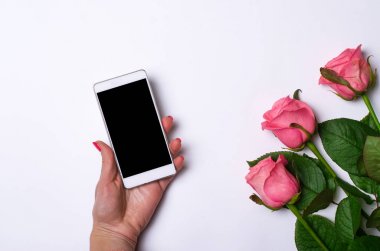 Beyaz bir arka plan üzerinde smartphone ve pembe güller.