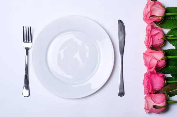 Decor voor een romantisch diner: bloemen en een plaat. — Stockfoto