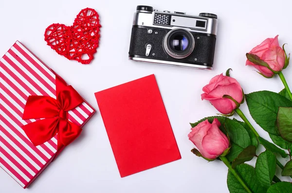 Romantische concept op witte achtergrond: rozen, cadeau en oude camera — Stockfoto