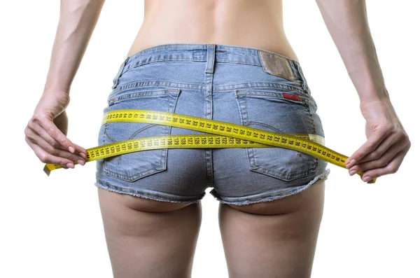 Wanita muda mengukur bokong dengan pita pengukur, mengisolasi — Stok Foto