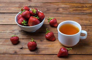 Sulu çilek ve ahşap bir tabloda çay.