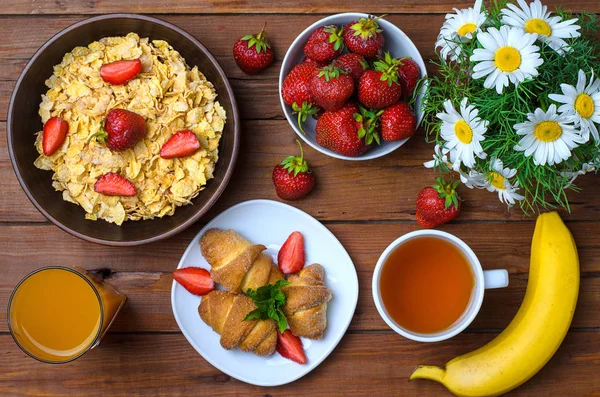 Здоровий сніданок: кукурудзяні пластівці, полуниця, сік, чай і крупа — стокове фото
