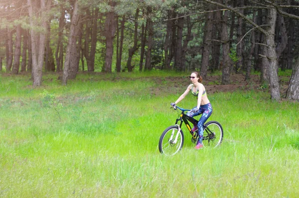 Una joven está montando en bicicleta en un sendero forestal. Esbelta gir — Foto de Stock