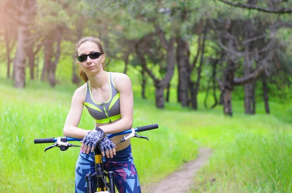 Mujer deportiva con una bicicleta en el bosque. Paseo en bicicleta de verano, fre — Foto de Stock