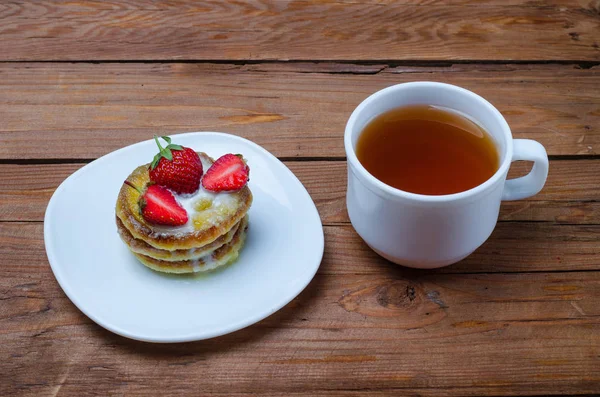 Чашка гарячого чаю і десерт з полуницею на дерев'яній табуретці — стокове фото