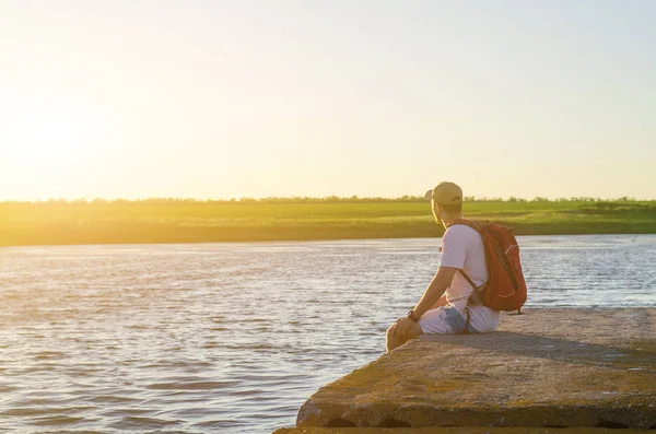 En man sitter på en flod pir och ser på solnedgången, gratis utrymme. — Stockfoto