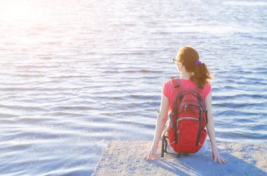 Genç kadın turist nehir iskele, kenarında oturan bir