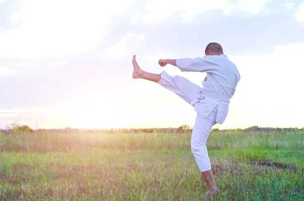 A sports man is training martial arts karate at sunset, a beauti